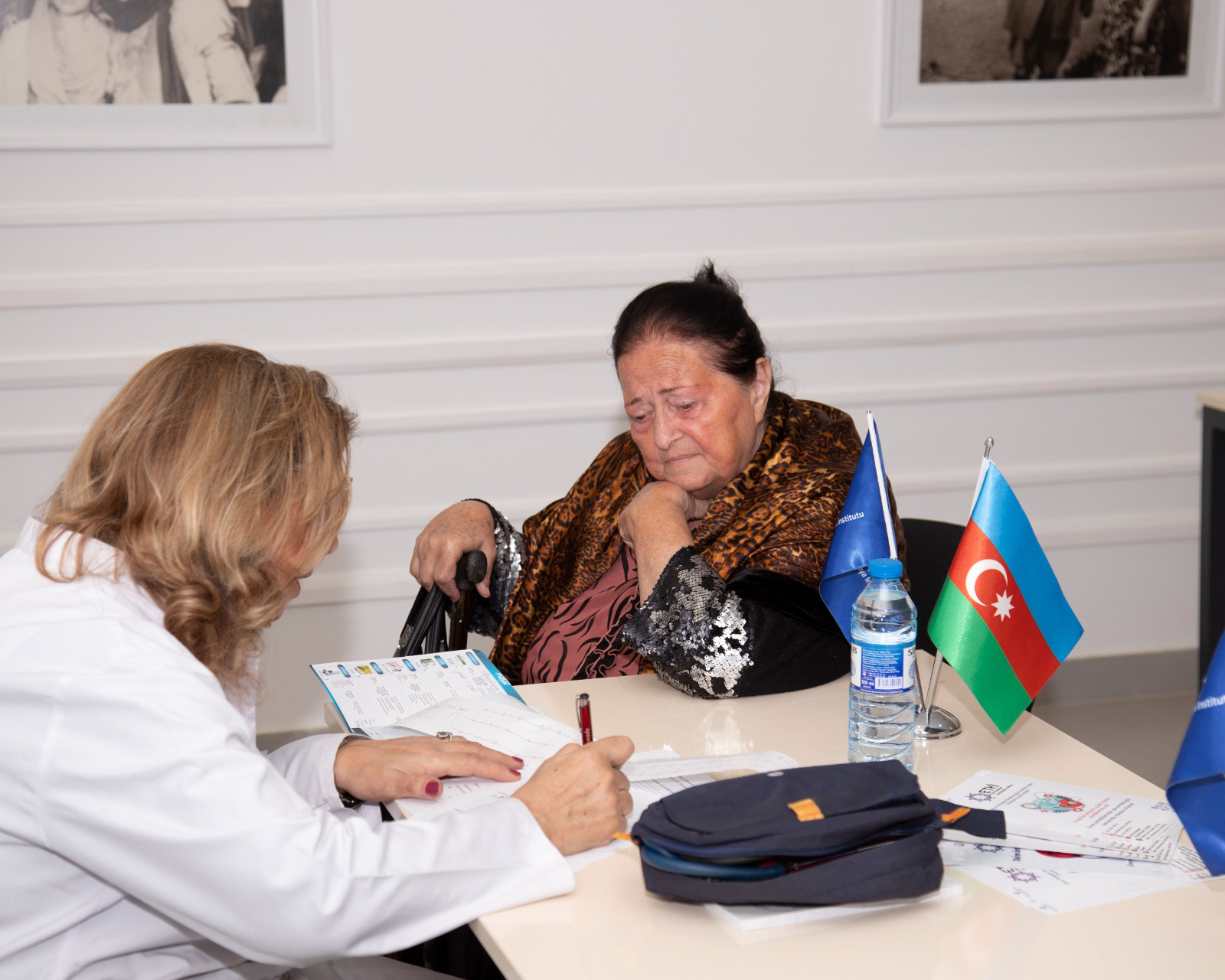 a woman and a man sitting at a table with papers and a flag