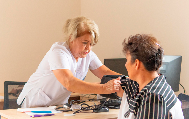 A healthcare professional checks a patient's blood pressure in a clinical setting.