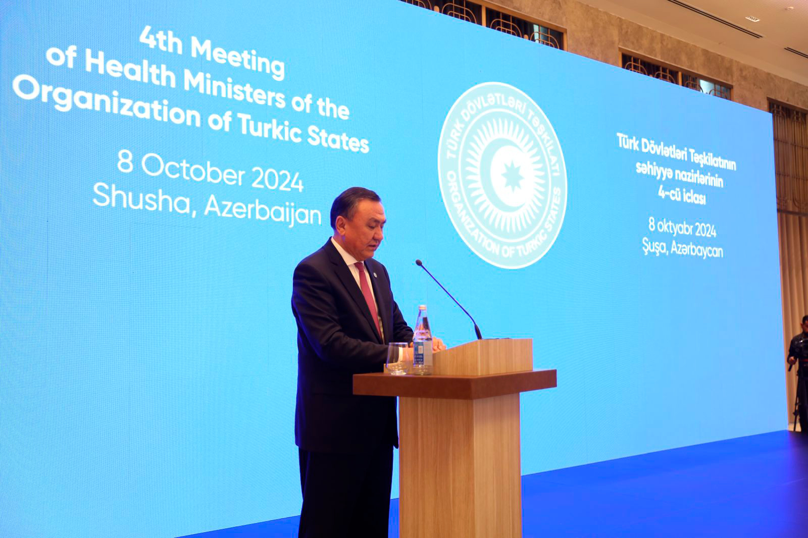 A speaker at a podium addresses an audience during the 4th Meeting of Health Ministers of the Organization of Turkic States in Shusha, Azerbaijan.