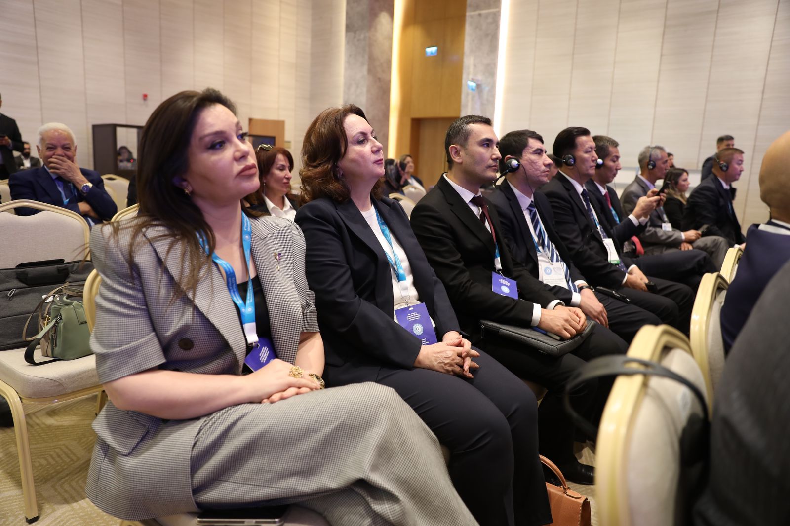 A group of attendees sitting in a conference room, wearing headsets and looking attentively at the front.