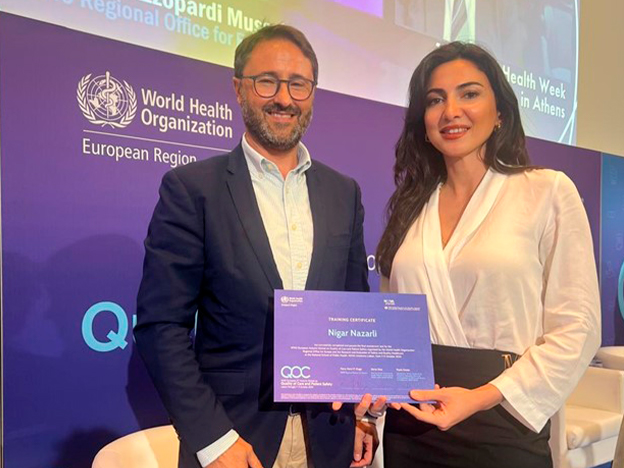 Two individuals are holding a training certificate at a World Health Organization event in Athens.