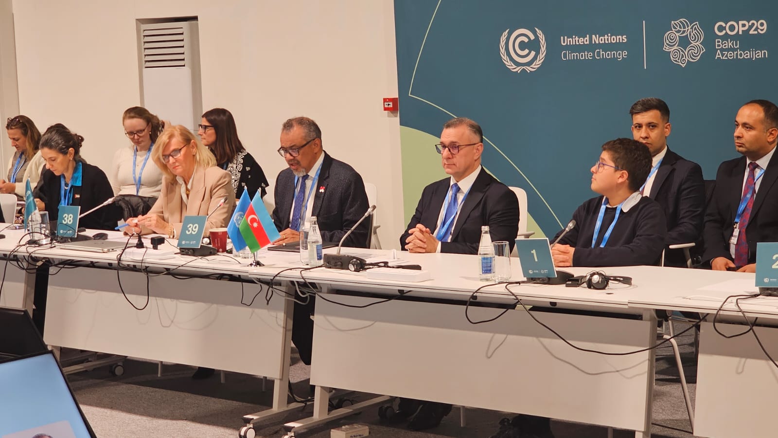 A group of people seated at a conference table with flags, engaged in discussions at COP29 in Baku, Azerbaijan.