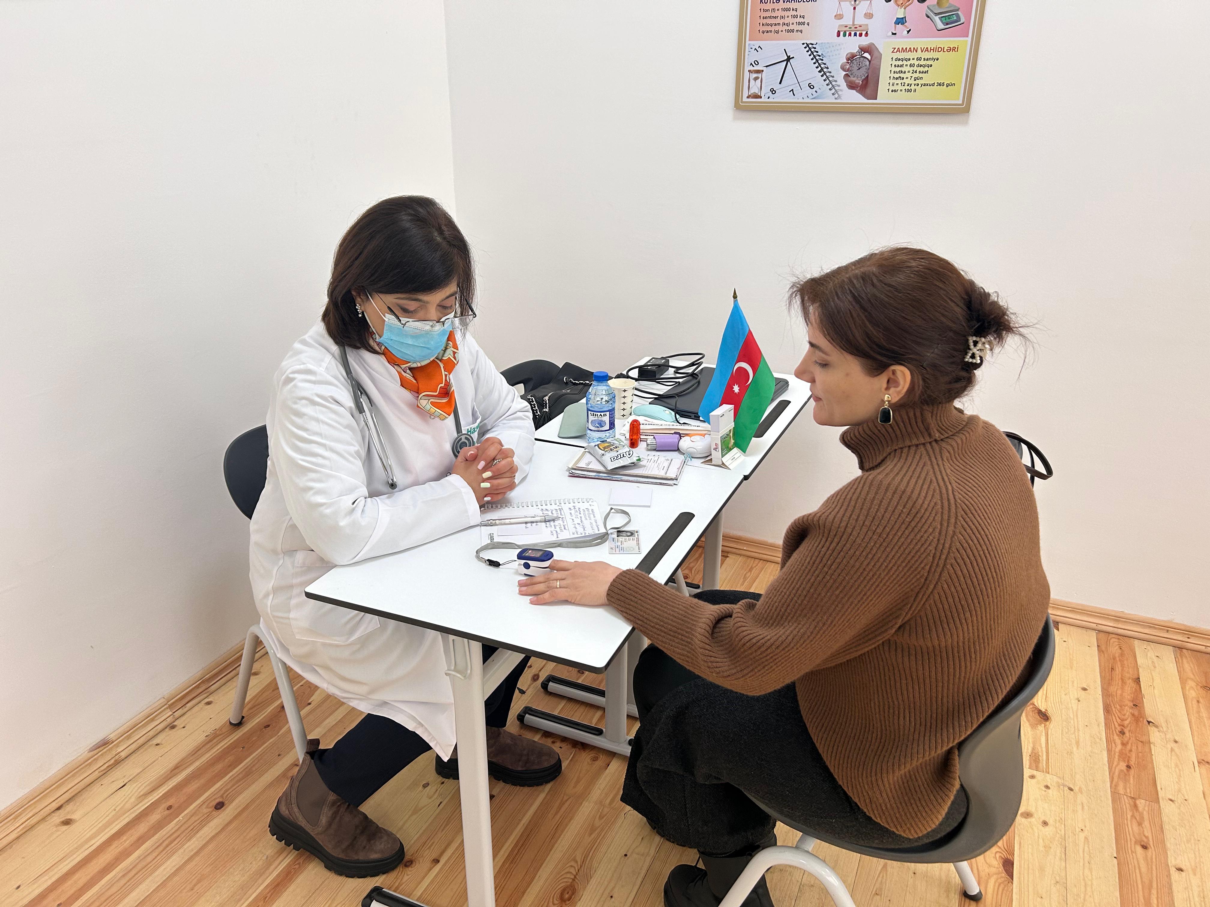 a person in a mask sitting at a table with another woman in a mask