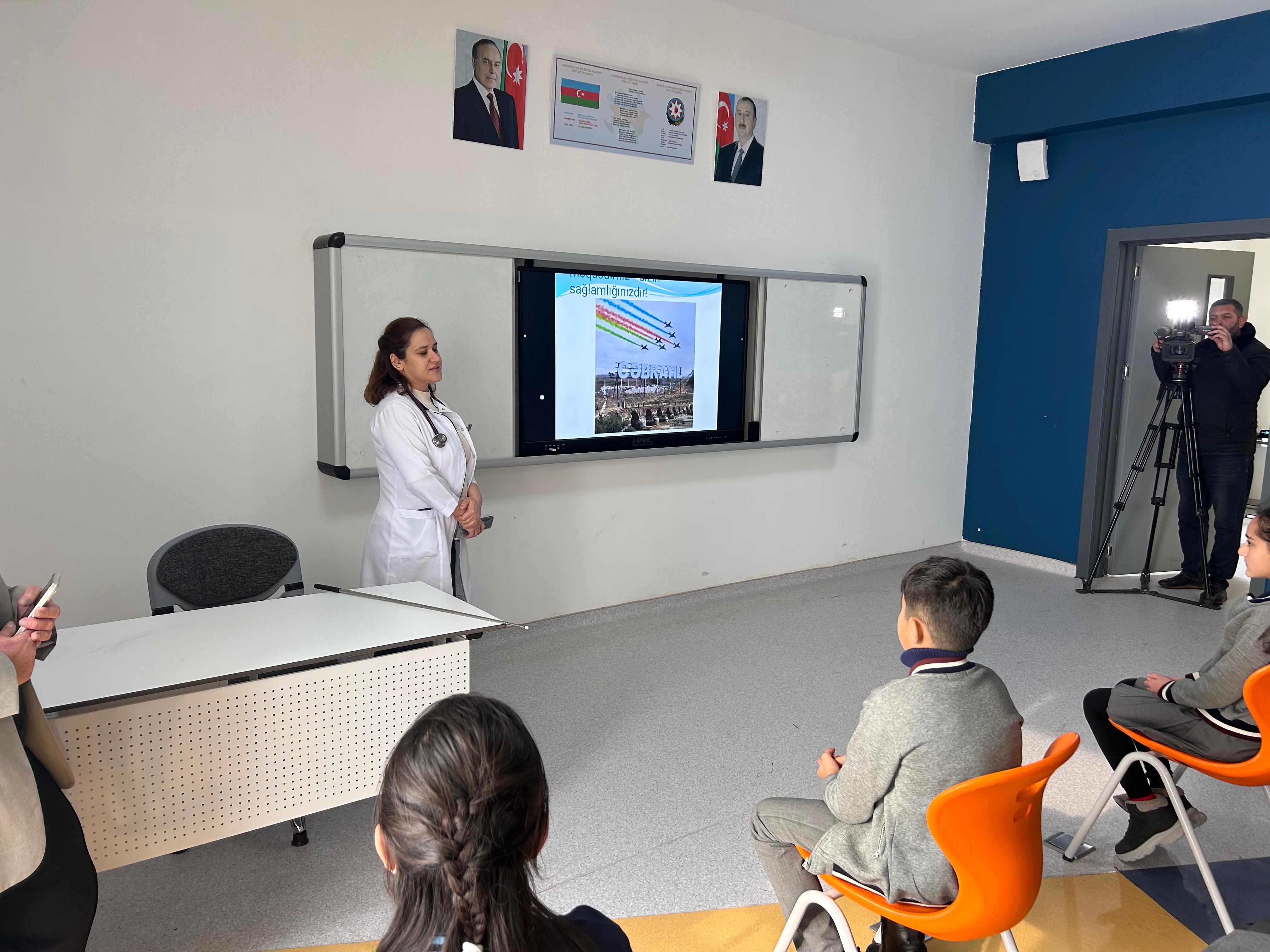 a person standing in front of a screen in a room with people