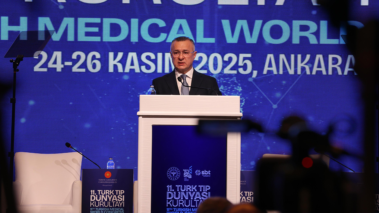 A speaker addresses an audience at the 11th Turkish Medical World Congress, with a backdrop displaying event details.