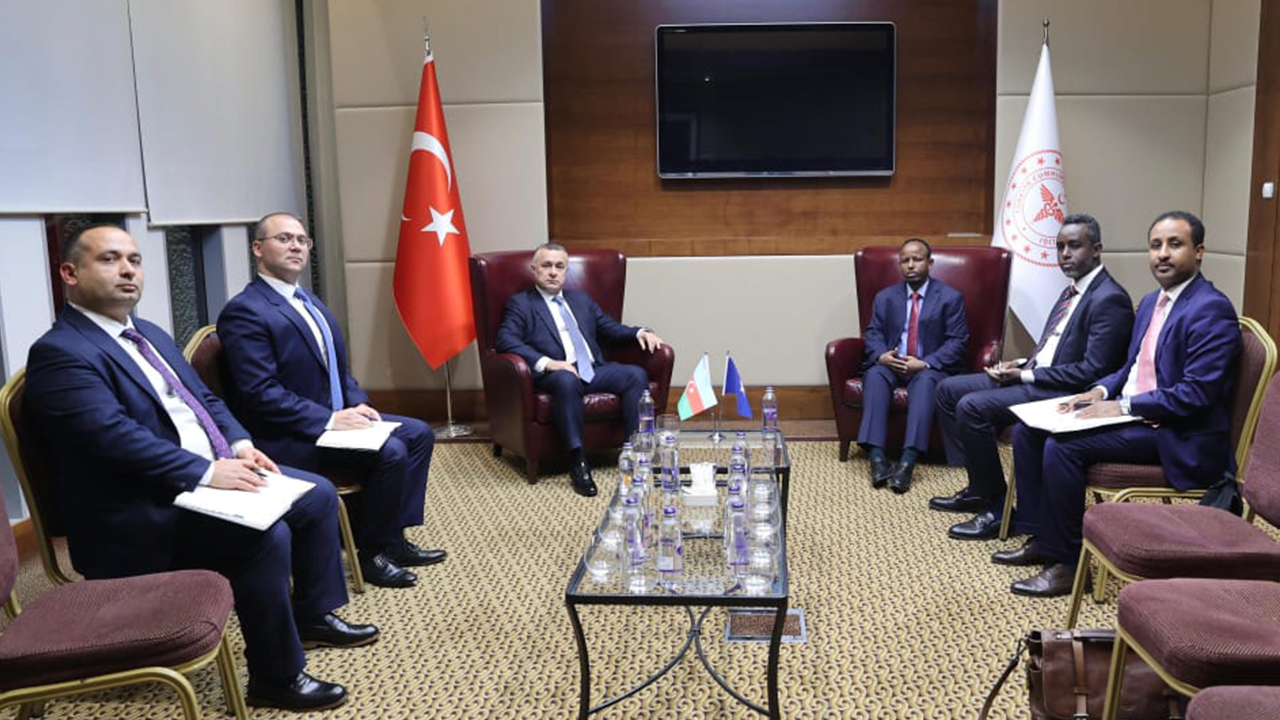 A group of six men in formal attire seated in a meeting room, with flags of Turkey, Azerbaijan, and the EU visible.