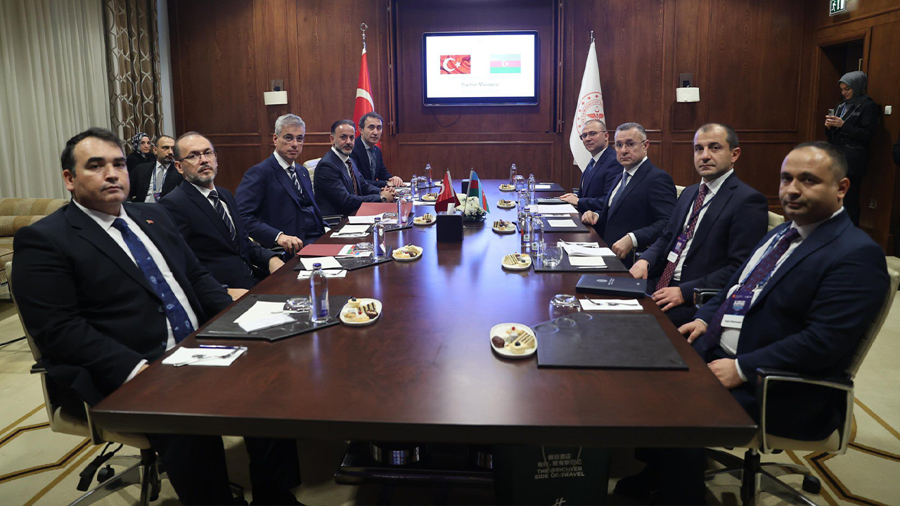 A group of officials seated around a conference table, with flags of Turkey and Azerbaijan displayed on a screen.