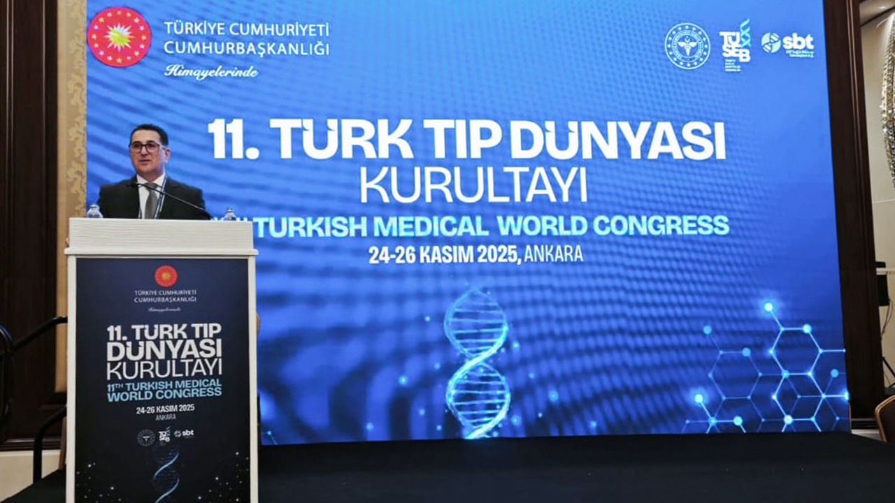 A speaker at a podium presents at the 11th Turkish Medical World Congress, with a digital backdrop displaying event details.